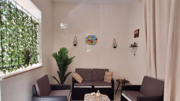 Una habitación amoblada con un sofá, dos sillones, una mesita y una planta en maceta.