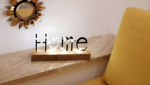 Una pared con tres espejos con forma de sol y un letrero que dice 'Home' sobre un estante de madera.