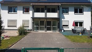 En toetagers bygning med balkon, store vinduer og en belagt indgang.