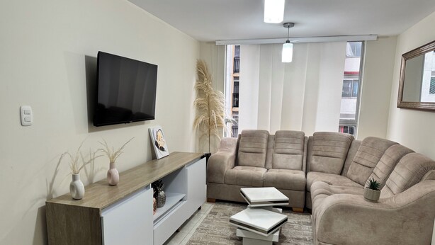 A living room with a sofa, TV, and a small table.