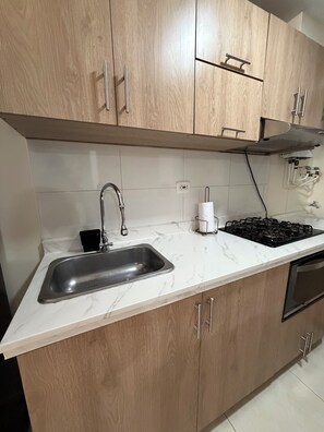 A kitchen with a sink, stove, and wooden cabinets.