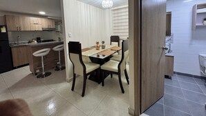 A modern kitchen with a dining area, including a chandelier, wooden cabinets, and a tiled floor.