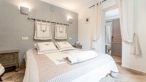 A bedroom with a bed, a nightstand, a wall-mounted towel rack, and a door leading to another room. - “Lavender Room” Guest Room with Shared Pool, Garden, and Wi-Fi (Bédoin)