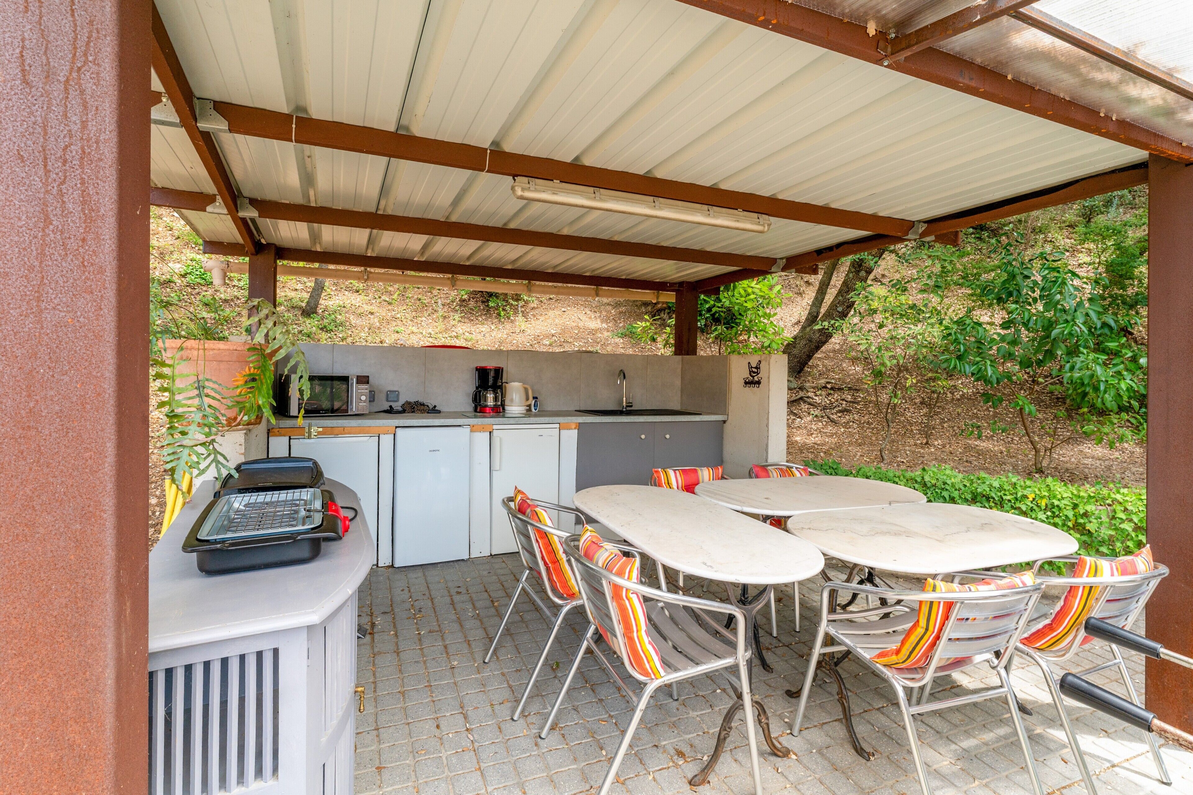 Une cuisine extérieure équipée d’une table et de chaises, d’un barbecue et d’une machine à café.