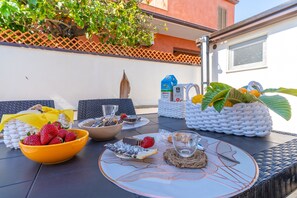 Une table dressée avec divers aliments, un bol de fraises, un panier de fruits et une bouteille de jus.