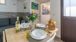 A dining table set with plates, glasses, a bottle of wine, and a vase of flowers. - ‘Trifamiliare Garden - Sole’ Apartment with Private Terrace, Wi-Fi, and Air Conditioning (Agnone)