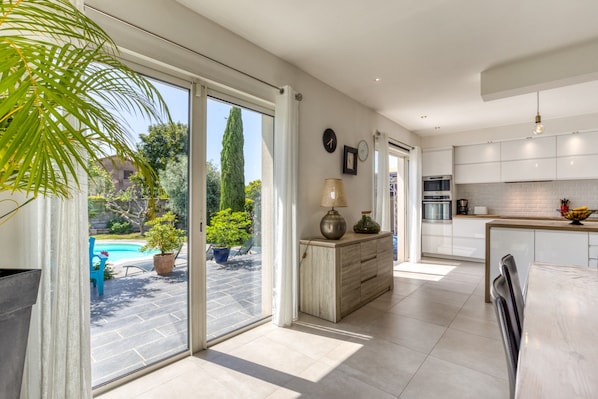 A spacious kitchen with a large island, a dining area with a table, and a sliding glass door leading to a pool area.