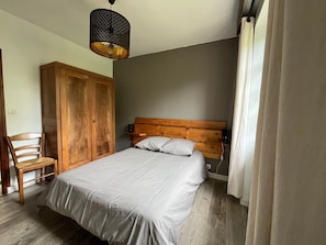 Ein Schlafzimmer mit einem hölzernen Bettgestell, einem Einzelbett, einem Holzschrank, einem Stuhl und einer Pendelleuchte.