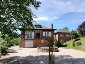 Ein zweistöckiges Backsteinhaus mit Veranda, Garage und kleinem Garten.