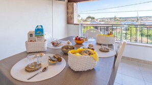 A dining table set with breakfast items, a TV mounted on the wall, and a balcony with a view. - Seaside Apartment 'Trifamiliare Garden - Conchiglia' with Private Terrace, Wi-Fi & AC (Agnone)