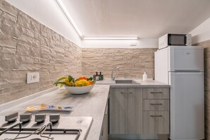 Une cuisine moderne avec un pare-feu en pierre, un four à micro-ondes encastré et un évier.