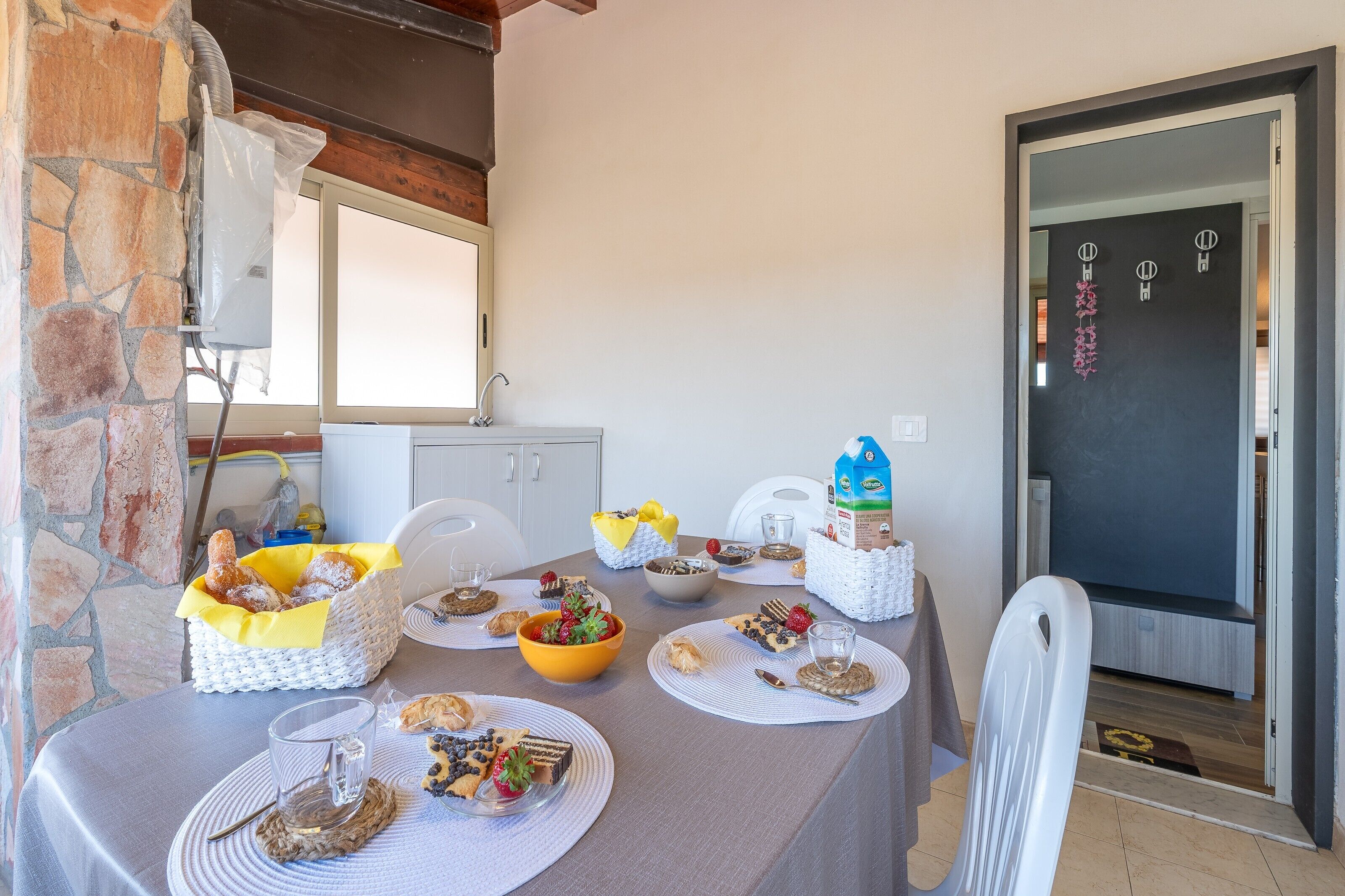 A dining table set with various dishes and a basket of pastries, a white cabinet, and a door with decorative elements.