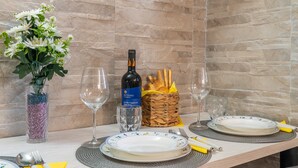 A dining table set with plates, glasses, a bottle of wine, a vase with flowers, and a basket of bread. - Seaside Apartment 'Trifamiliare Garden - Conchiglia' with Private Terrace, Wi-Fi & AC (Agnone)