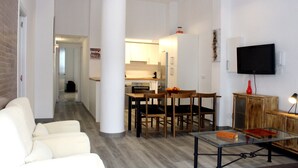 Ein modernes Wohnzimmer mit einer Couch, einem Glastisch und einem Fernseher an der Wand.