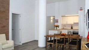 Eine moderne Küche mit weißen Schränken, einem Esstisch mit Stühlen, Holzboden und Ziegelwand.