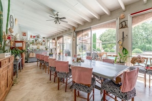 Una cocina amplia con zona de comedor, ventanas grandes y un ventilador de techo.