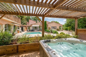 Une terrasse en bois avec un jacuzzi, une piscine et un espace patio couvert.