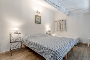 Een slaapkamer met een bed, twee nachtkastjes, een wandlamp, een schilderij en een raam met gordijnen.