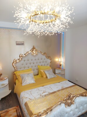 A bedroom with a tufted headboard, a chandelier, and a bedside table with a lamp. - Venetian-Style Guest Room 24 m² with Mountain View, Wi-Fi, Air Conditioning (Égliseneuve-près-Billom)