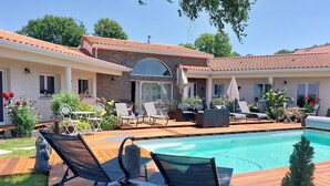 Un patio trasero con piscina, sillas de descanso y una mesa.