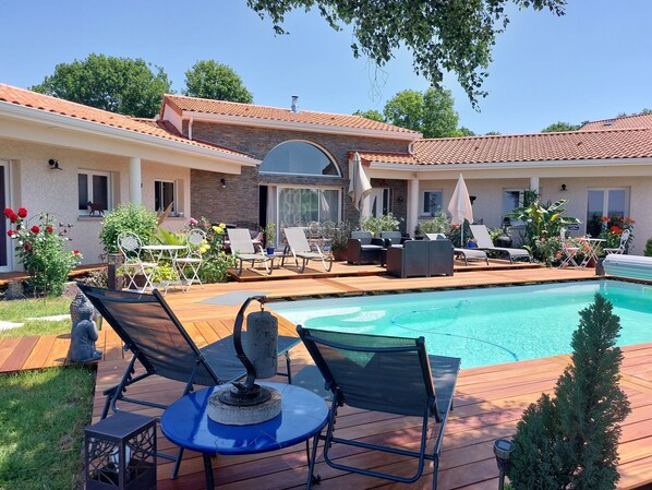A backyard with a swimming pool, lounge chairs, and a patio table.