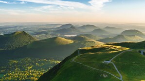 Vista panorámica de un paisaje montañoso con una carretera sinuosa y cielo despejado.
