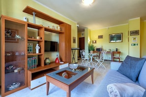A living room with a sofa, coffee table, wooden shelving, and a TV.