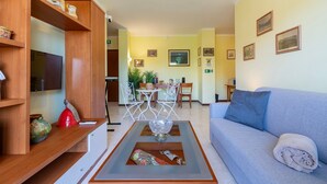 Una sala de estar con sofá, una mesa de centro, televisor y un comedor con sillas y mesa.