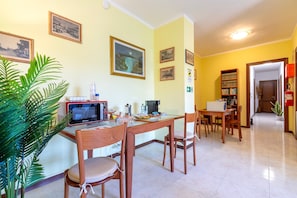 A dining area with a table, chairs, a microwave, and a plant.