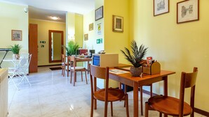 Un comedor de hotel con mesas y sillas de madera, obras de arte en las paredes y una señal de salida a la vista.
