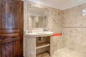 Une salle de bain avec un meuble-lavabo en bois, un lavabo avec un miroir et un espace douche.