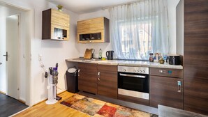 A modern kitchen with wooden cabinets, a built-in oven, and a window with sheer curtains. - Apartment “Central Hemer Near Lung Clinic” with Wi-Fi (Hemer)