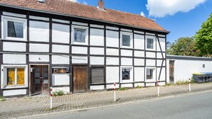A traditional half-timbered building with a tiled roof, a paved sidewalk, and a chain-link fence. - Apartment “Central Hemer Near Lung Clinic” with Wi-Fi (Hemer)