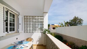Ein Balkon mit Esstisch, einem Zierbildschirm und Blumentöpfen.