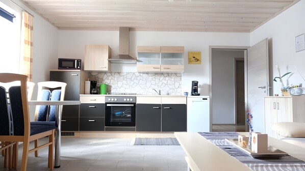 A modern kitchen with a microwave, coffee maker, and dishwasher. There is a dining area with a table and chairs.