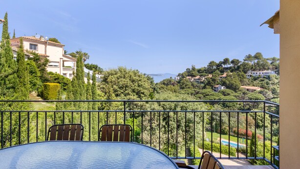 A balcony with a table and chairs, overlooking a residential area with trees and houses. - Semi-detached house with sea views and communal pool (Begur)