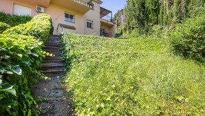 A residential building with a staircase leading to the entrance, surrounded by lush greenery and a clear sky. - Semi-detached house with sea views and communal pool (Begur)
