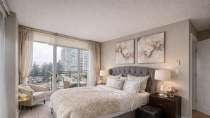 A bedroom with a large bed, a nightstand, a dresser, and a view of a balcony. - Ocean View Downtown (White Rock)