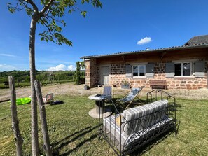 Une maison en pierre dotée d’une terrasse, de mobilier d’extérieur et offrant une vue sur la campagne.
