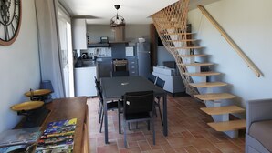 Een moderne keuken met een eethoek, een trap en een grote klok aan de muur.