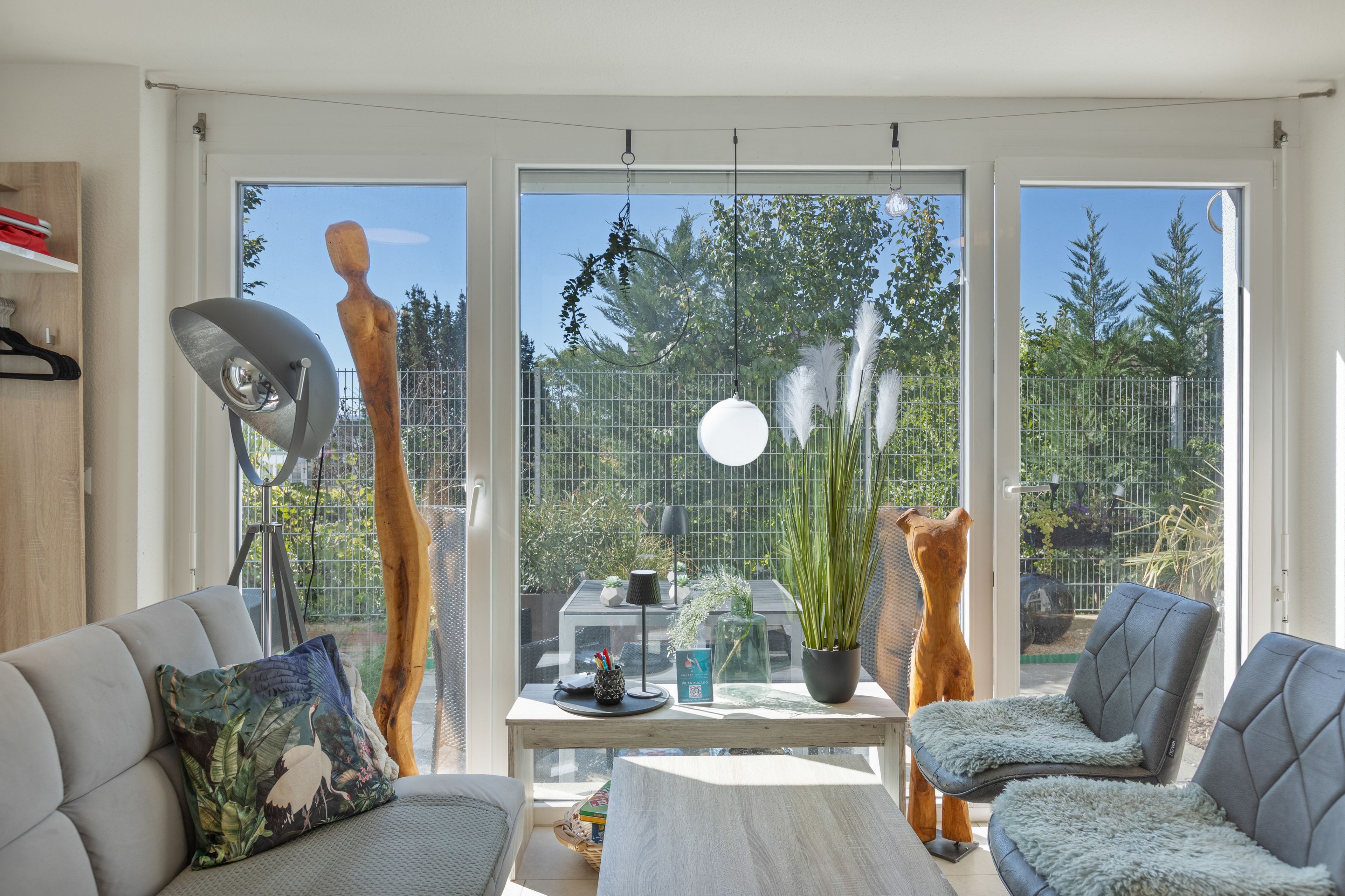 Una sala moderna con sofá, sillón y una mesa con objetos decorativos.