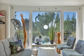 Una sala moderna con sofá, sillón y una mesa con objetos decorativos.