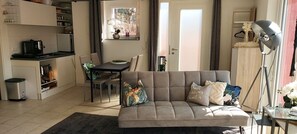 Ein Wohnzimmer mit Sofa, Esstisch und Küchenzeile.
