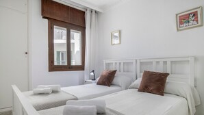 A hotel room with two beds, a window with curtains, a nightstand with a lamp, and a framed picture on the wall. - Apartment 'Marítimo' with Sea Views and Private Terrace (Barbate)