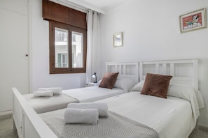 Ein Hotelzimmer mit zwei Betten, einem Fenster mit Vorhängen, einem Nachttisch mit Lampe und einem gerahmten Bild an der Wand.
