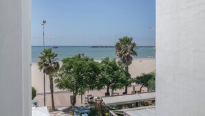 A view of a beach with palm trees and a pier in the distance. - Apartment 'Marítimo' with Sea Views and Private Terrace (Barbate)