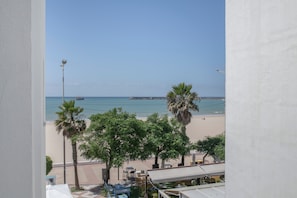 Blick auf einen Strand mit Palmen und einem Pier im Hintergrund.