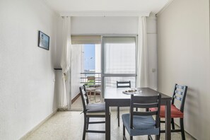 A dining area with a table and chairs, a view through a window, and a door leading to an outdoor balcony.
