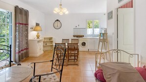 Une pièce comprenant une table à manger, des chaises, un lit, un lave-linge, un évier et une fenêtre avec des rideaux.