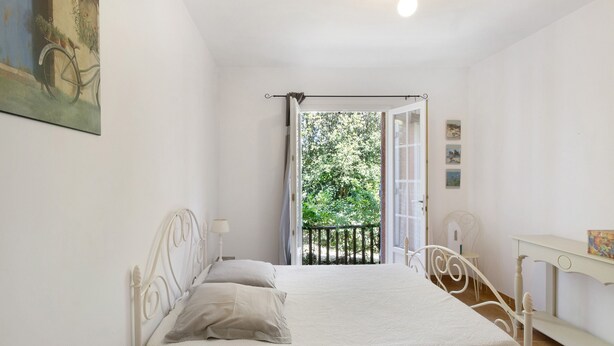 Une chambre avec un lit, un bureau et un balcon donnant sur la forêt.